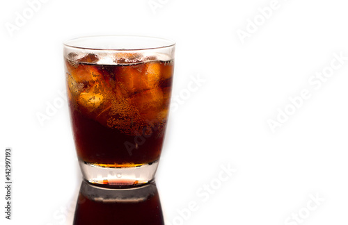A glass of ice filled with ice,.Black soda in glass