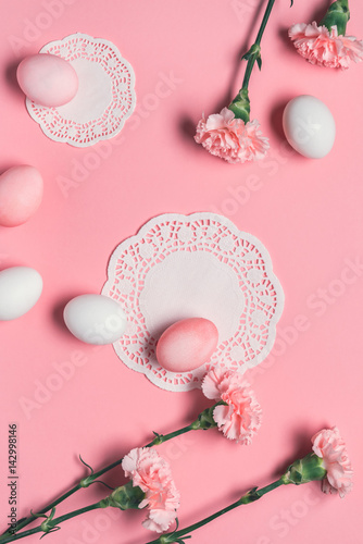 top view of pink and white eggs with flowers and lace napkins on pink. Happy Easter concept