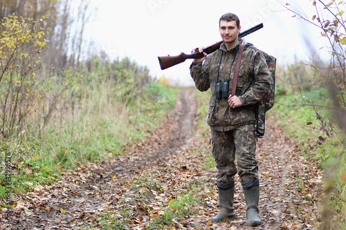 Man in camouflage and with guns in a forest belt on a spring hun