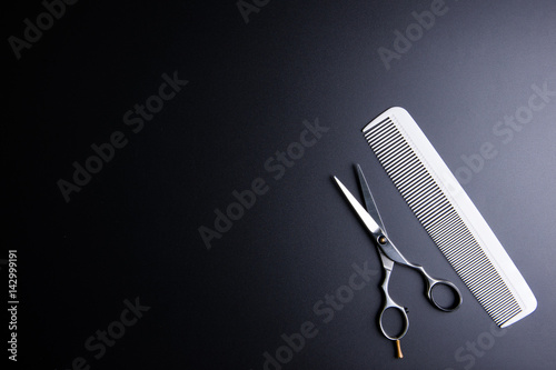 Stylish Professional Barber Scissors and white comb on black background. Hairdresser salon concept, Hairdressing Set. Haircut accessories. Copy space image, flat lay.