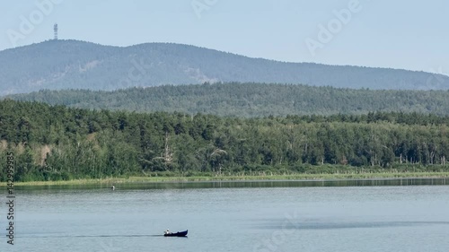 Motor boat rides on a mountain river. Place of meteorite fall. Chebarkul lake. Mountain forest. Panorama. Gray sky. Small fog. Haze. Autumn in the Ural Mountains. photo