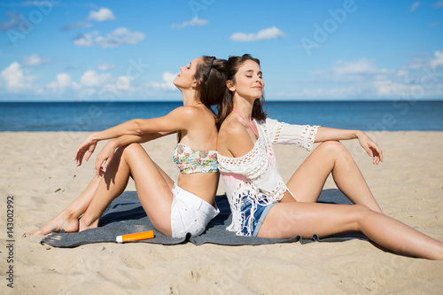 Two pretty girls relaxing on beach sunbathing