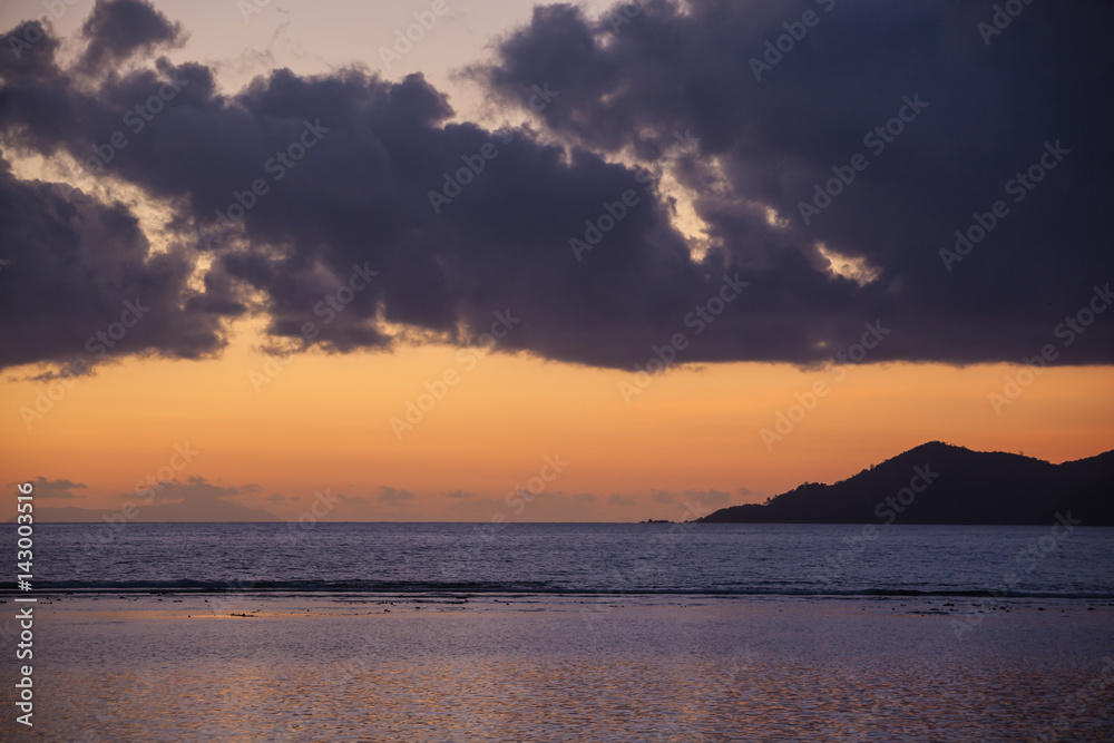 Orange sunset in dark clouds above Indian ocean, Seychelles