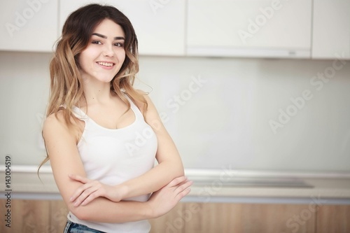 Pretty young woman standing in kitchen and smiling.