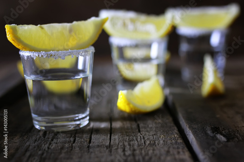 stack of tequila with salt and lemon on a wooden background