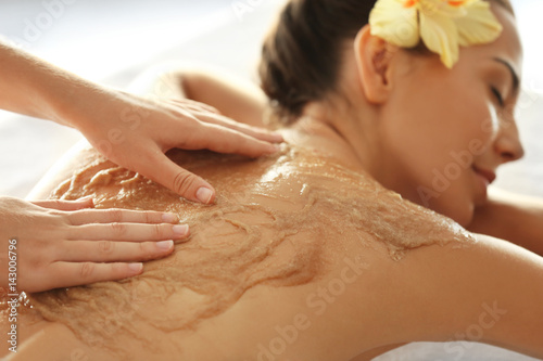 Young woman receiving scrub massage in spa salon