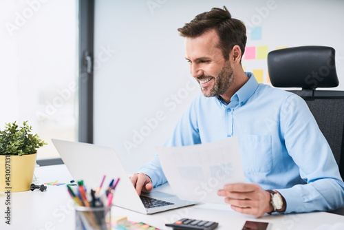 Fotografie Happy businessman doing data entry work at office