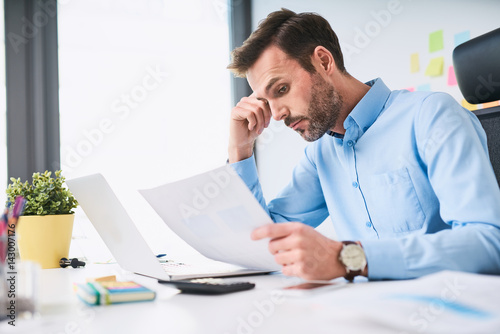 Unhappy businessman doing paperwork at office photo