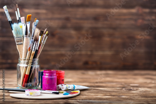 Artist's workshop. Top view of paintbrushes palette and acrylic paints with white canvas. Set of brushes and oil paints. Art picture with copy space and for add text.Items for children's creativity
