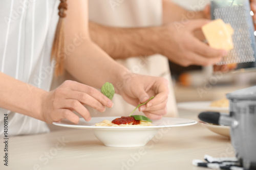 Woman hands decorating pasta on kitchen table
