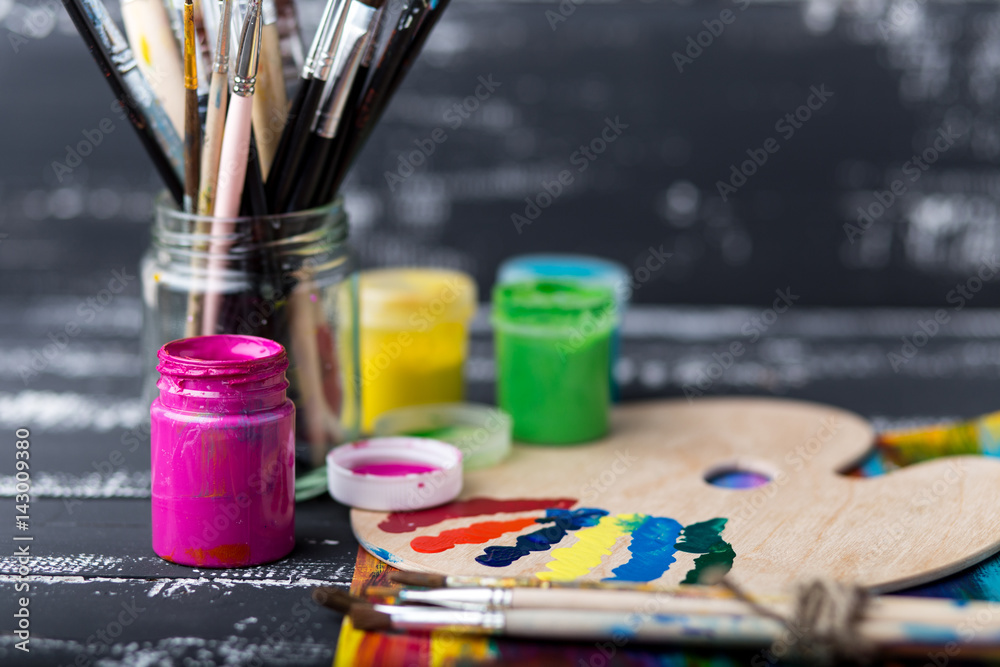 Wooden art palette with tubes of oil paints and a brush. Art and craft tools. Artist's brush, canvas, palette knife. Space for text. Items for children's creativity.Acrylic paint and brushes Wooden art palette with tubes of oil paints and a brush. Art and craft tools. Artist's brush, canvas, palette knife. Space for text. Items for children's creativity.Acrylic paint and brushes