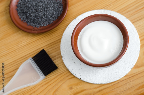 Small ceramic bowls with sour cream (greek yogurt) and poppy seeds. Ingredients for preparing facial mask or scrub. Homemade cosmetics 