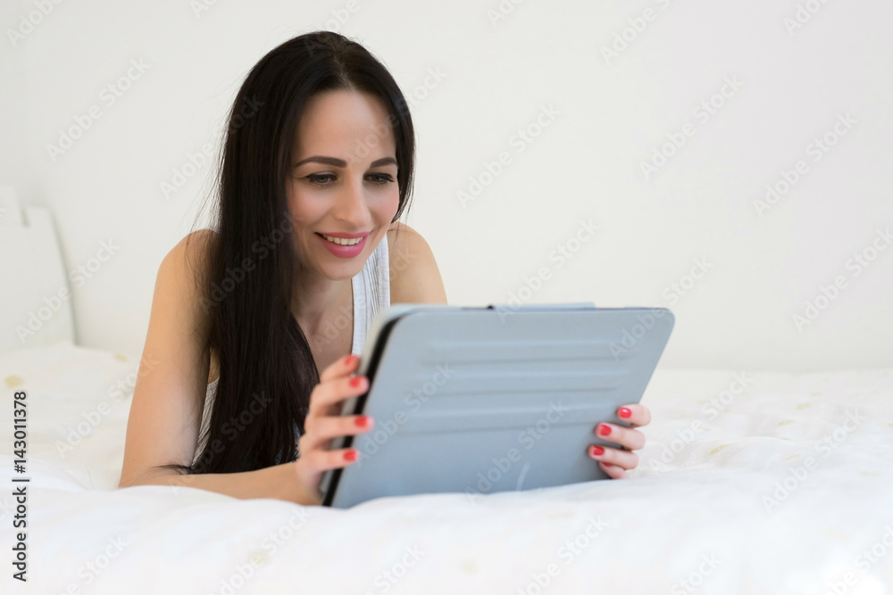 A woman lies on her bed using her tablet A woman lies on her bed using her tablet