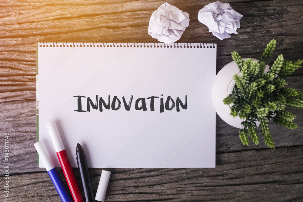 Fotografie Innovation word with Notepad and green plant on wooden background