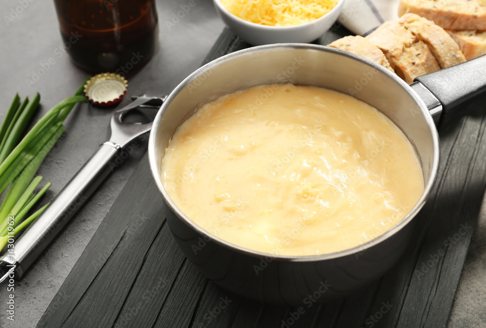 Saucepan with beer cheese dip on wooden board Saucepan with beer cheese dip on wooden board