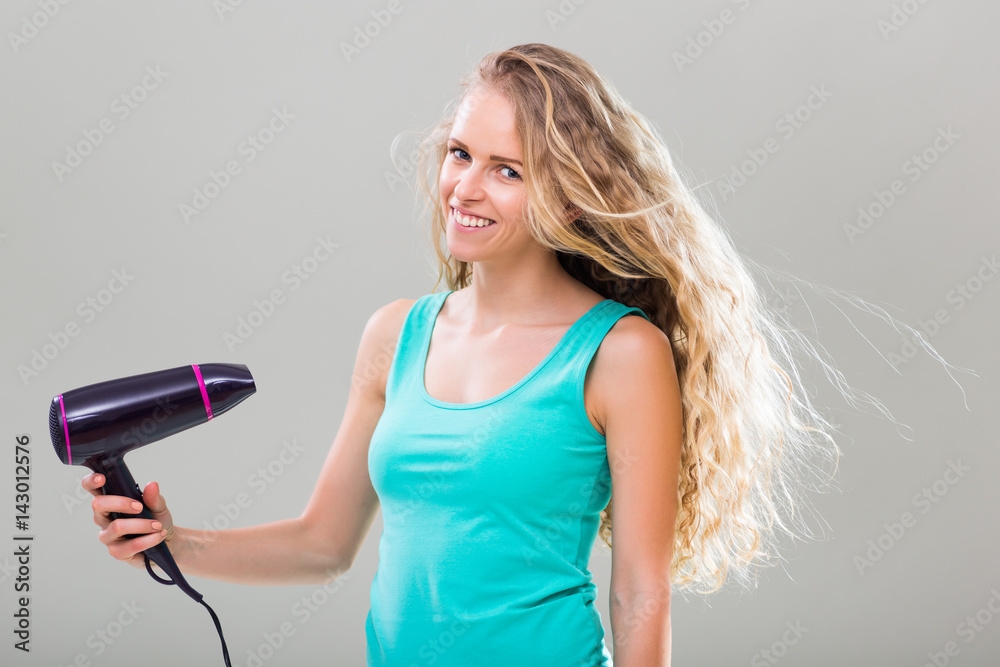 Young woman with gorgeous long blonde hair using hairdryer. Young woman with gorgeous long blonde hair using hairdryer.