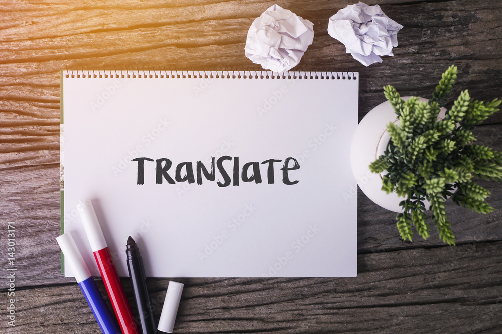 Φωτογραφία Translate word with Notepad and green plant on wooden background.