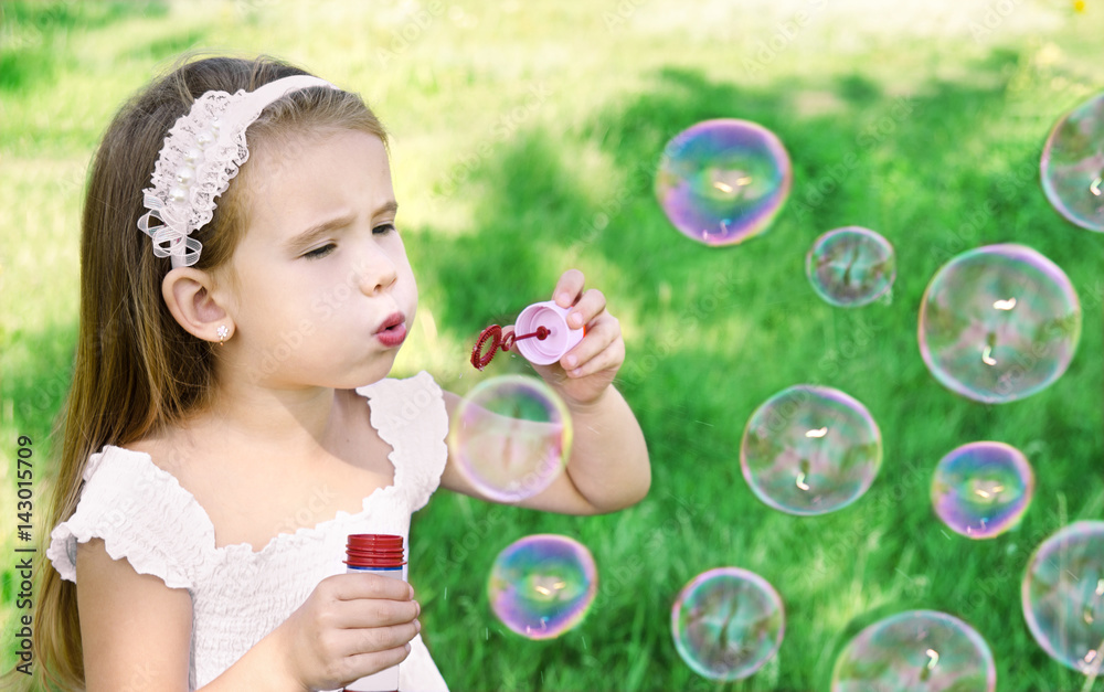 Cute little girl is blowing a soap bubbles