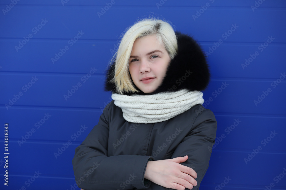 Young beautiful girl on a walk in winter at blue wall Young beautiful girl on a walk in winter at blue wall