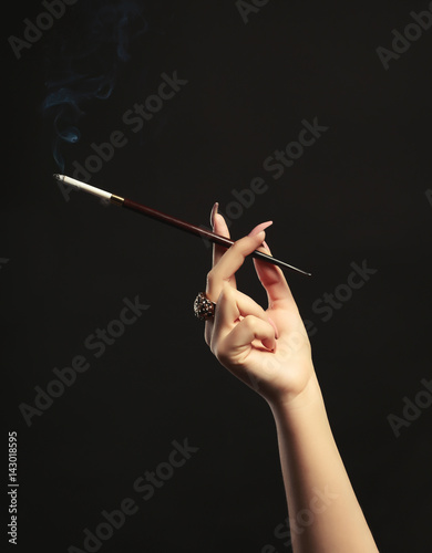 Female hand with cigarette holder on dark background
