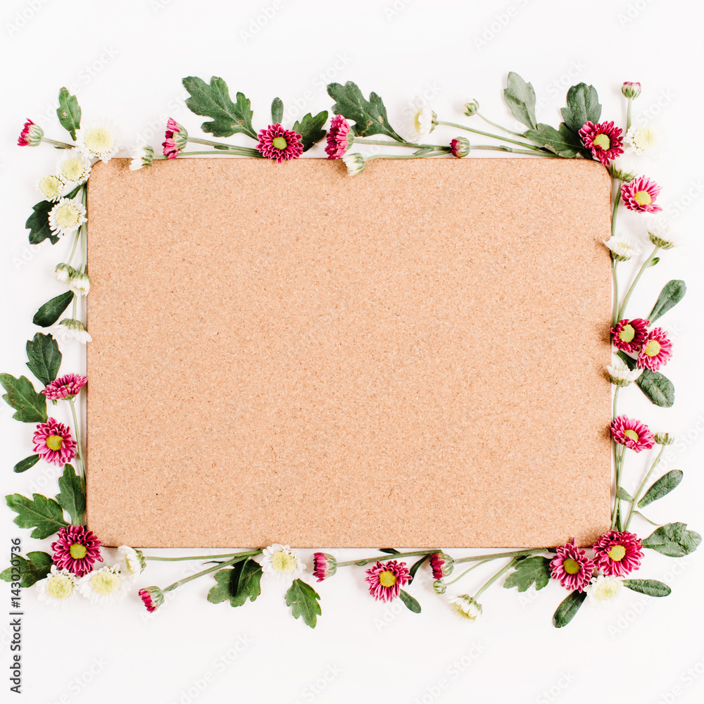 Frame with red and white wildflowers, green leaves, branches and wooden cork tree board on white background. Flat lay, top view. Flower background.