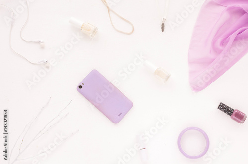 Feminine accessories. Desk workspace with white fashion accessories, purple phone, lilac shawl on white background. Flat lay, top view, mock up