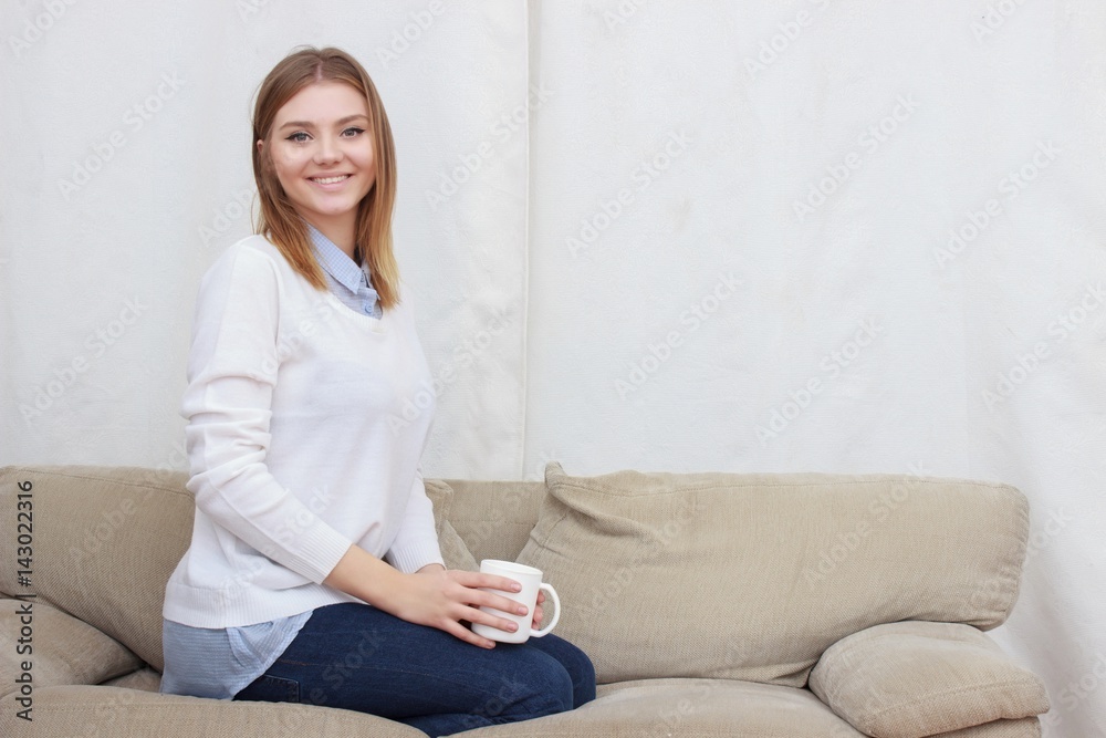 woman sitting on couch in her living room and drinking coffee