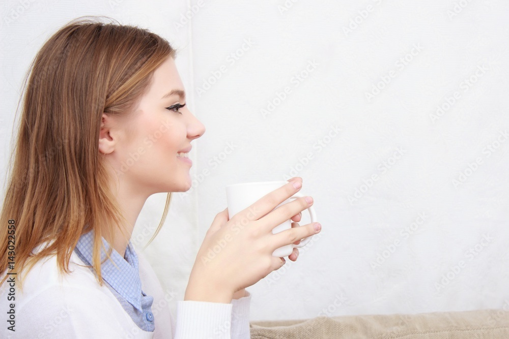 woman sitting on couch in her living room and drinking coffee woman sitting on couch in her living room and drinking coffee
