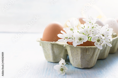 Easter eggs with spring flowers on light background. Copy space selective focus. Easter photo concept