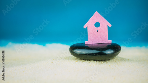 Symbol of little lilac house secured builed on black stone on blue background photo