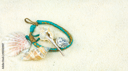 Sea shells and coloured wristbandon on sandy beach