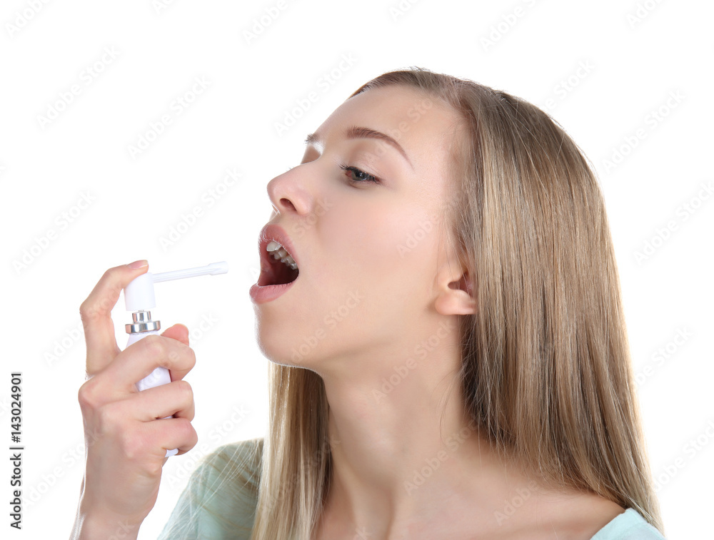 Sick young woman using throat spray on white background Sick young woman using throat spray on white background