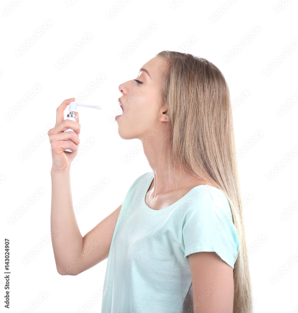 Sick young woman using throat spray on white background Sick young woman using throat spray on white background