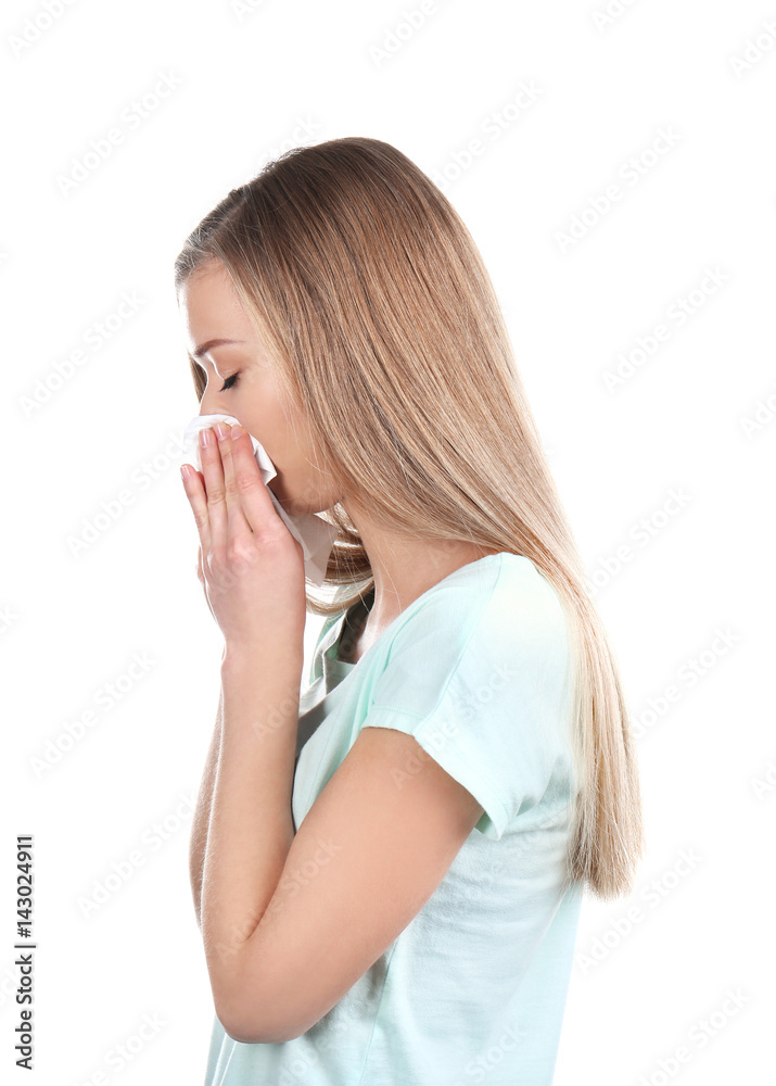 Sick young woman blowing nose on tissue against white background Sick young woman blowing nose on tissue against white background