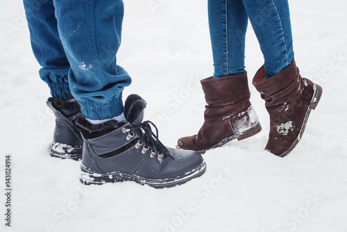 Closeup of male and female legs during a date in winter, shorter woman slid up to reach taller man on love scene, couple kissing.