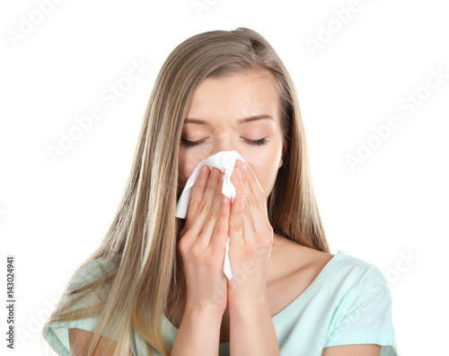 Young woman blowing nose on tissue against white background