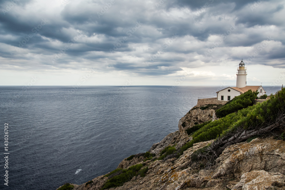 Amazing lighthouse Cala Ratjada is located in the easternmost part of Mallorca on the cliff. Lighthouse in cloudy day with beautiful view on the ocean. Balearic Island Mallorca, Spain.