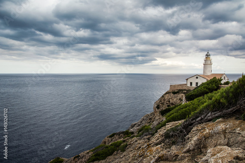 Amazing lighthouse Cala Ratjada is located in the easternmost part of Mallorca on the cliff. Lighthouse in cloudy day with beautiful view on the ocean. Balearic Island Mallorca, Spain. © kralovecphoto