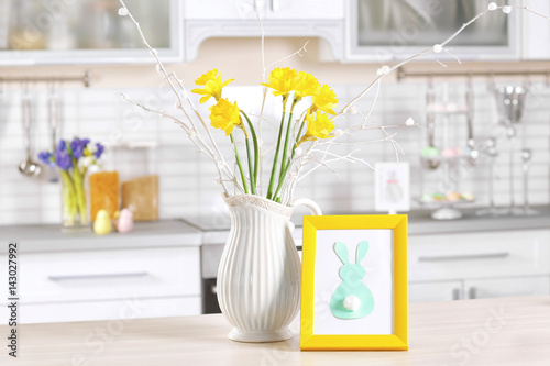 Narcissus in vase with Easter decorations against blurred background