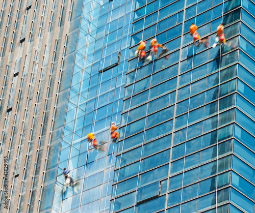 Workers of steeplejack washing windows of the modern building.