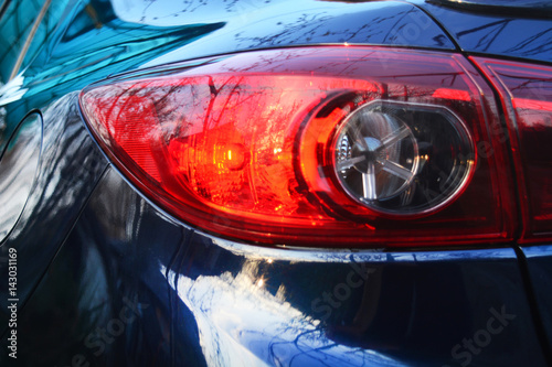 Red tail-light on a dark blue car.