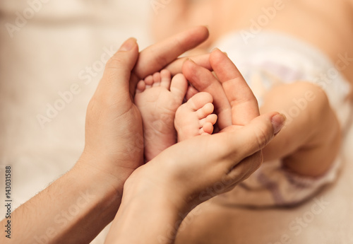 Mother holding tiny foot of newborn baby