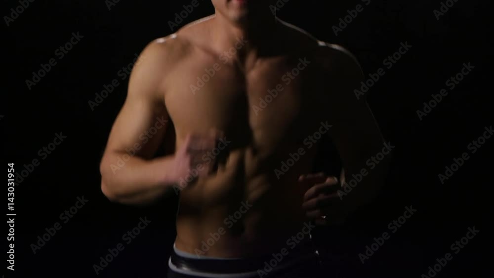Man athlete running at fast pace on black background. Studio