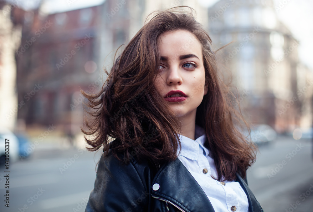 Amazing joyful pretty girl with long brunette hair. posing outdoor. leather jacket,brunette hair, bright red lips Close up fashion street stile portrait