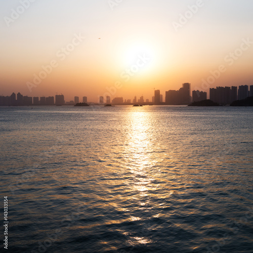 Silhouette buildings of a city with reflection in water. China