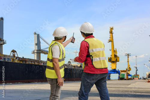 Port and safety controler surveying the port terminal with ship berthing wharf in background photo