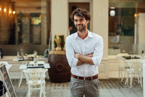 handsome man standing outside in front of his restaurant