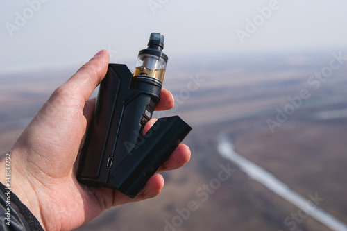 Black electronic cigarette in the hands of a man