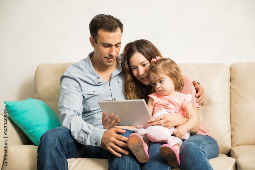 Sweet Little kid watching tablet with mom and dad