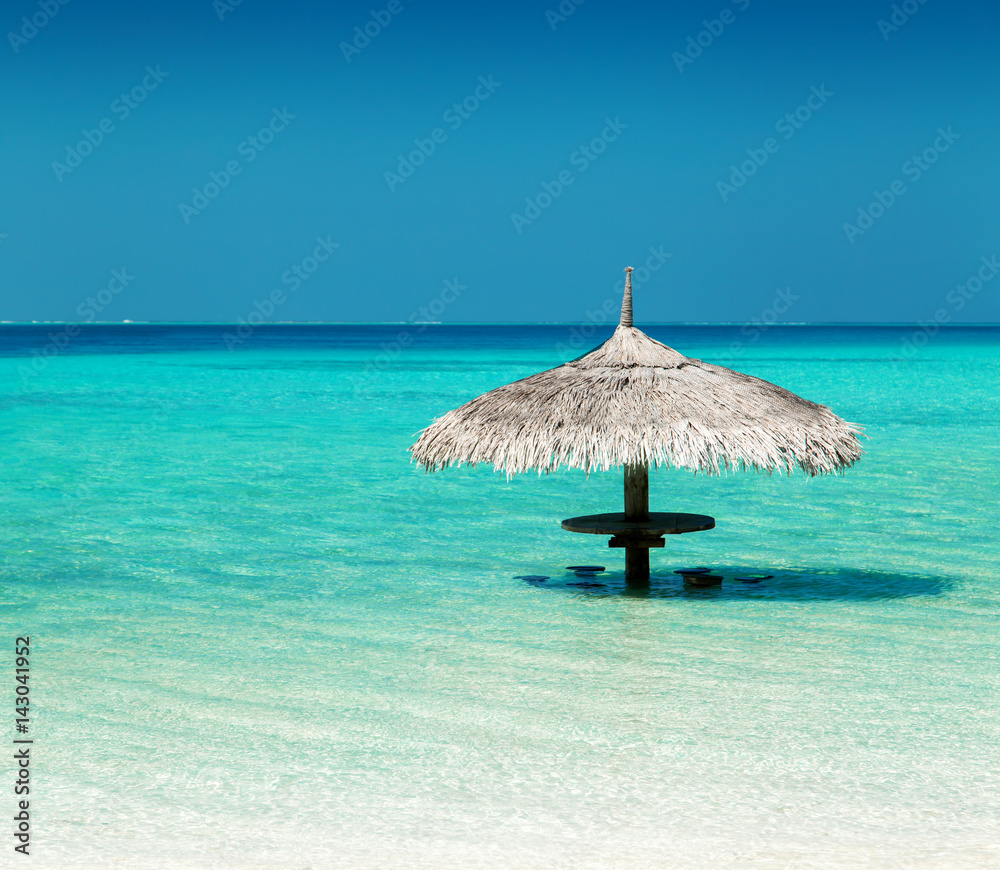 Straw parasol on water at tropical island Stock Photo | Adobe Stock